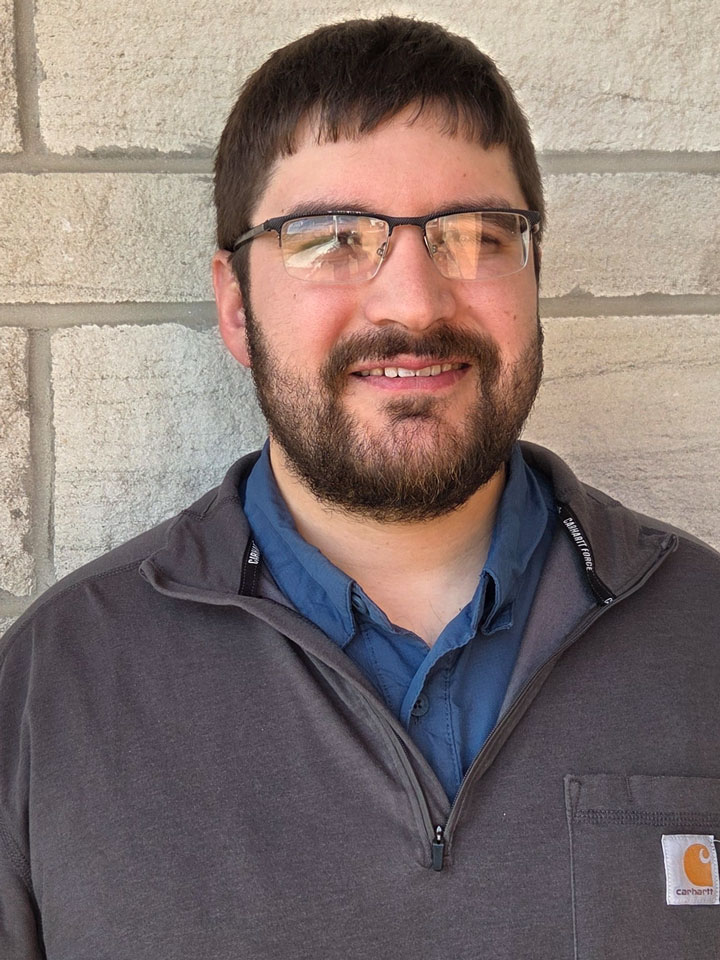 Casey Lobdell. Man with short dark brown hair, a beard and mustache. He is shown wearing glasses and a blue work shirt.