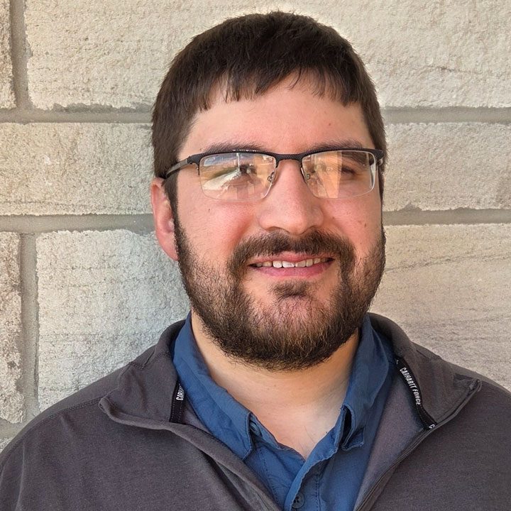 Casey Lobdell. Man with short dark brown hair, a beard and mustache. He is shown wearing glasses and a blue work shirt.